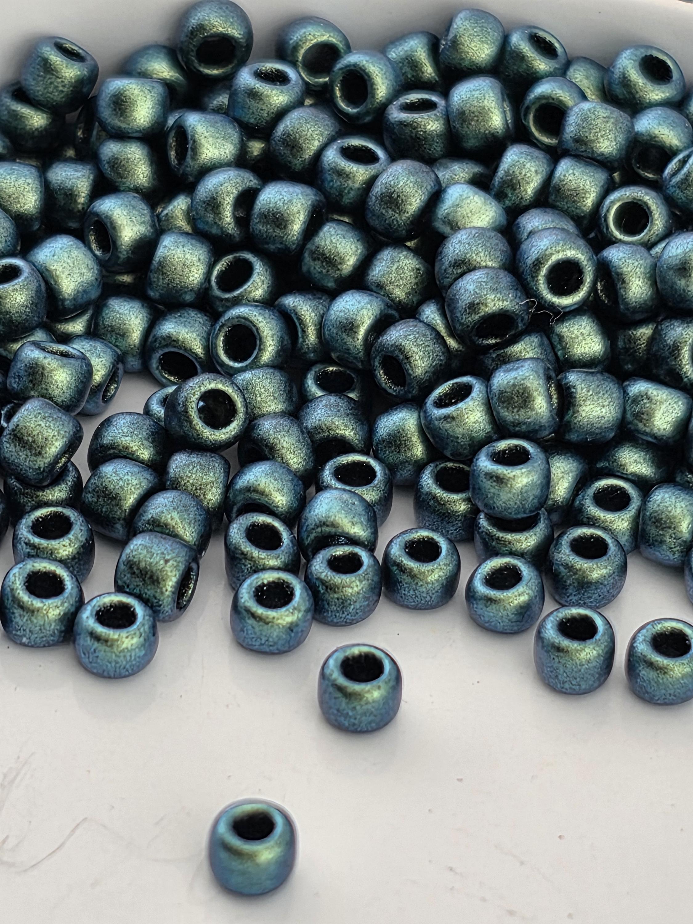a large pile of small, shiny blue beads scattered on a white surface.