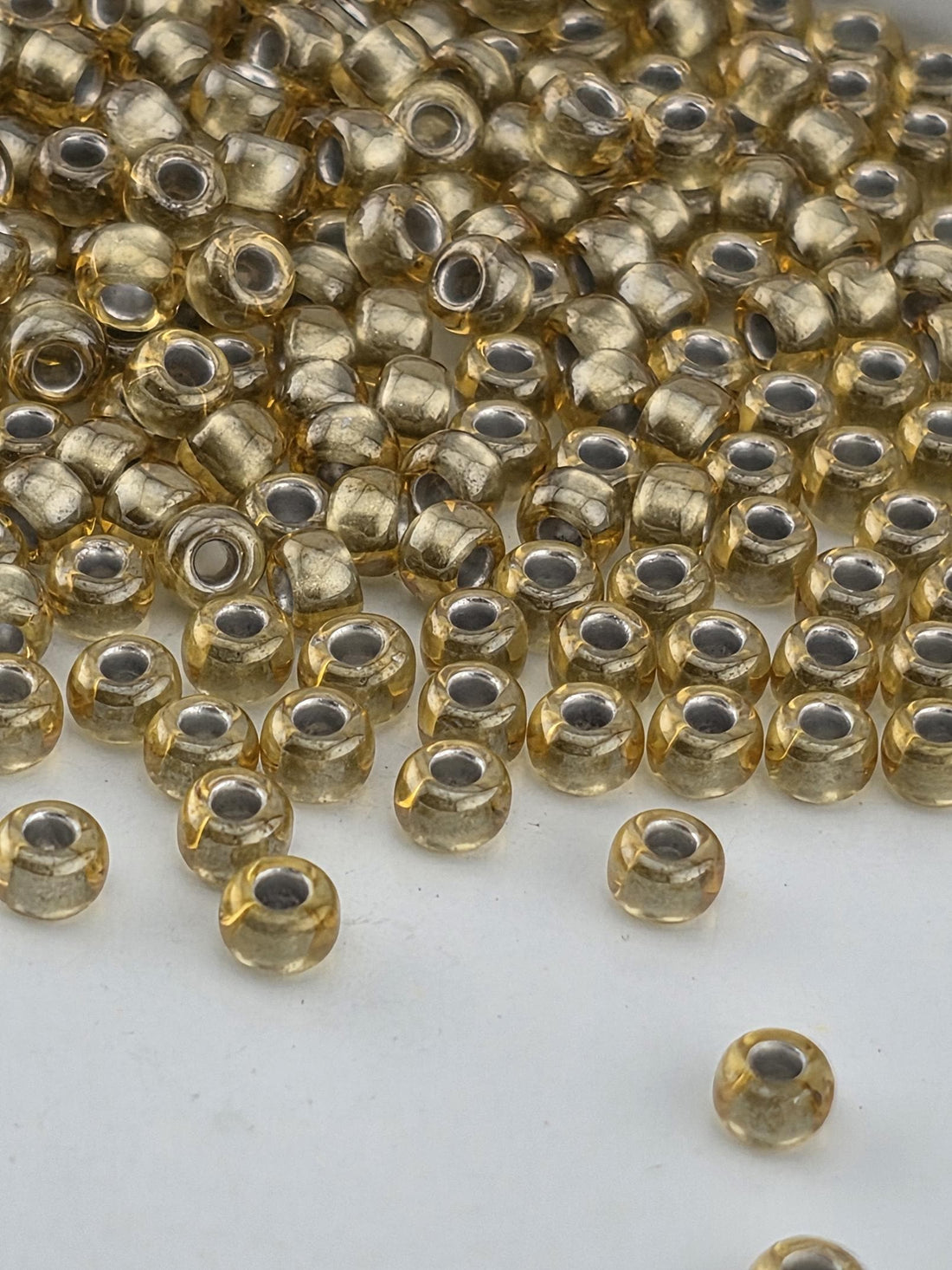 a close-up view of numerous small, round, golden-colored beads scattered across a white surface.