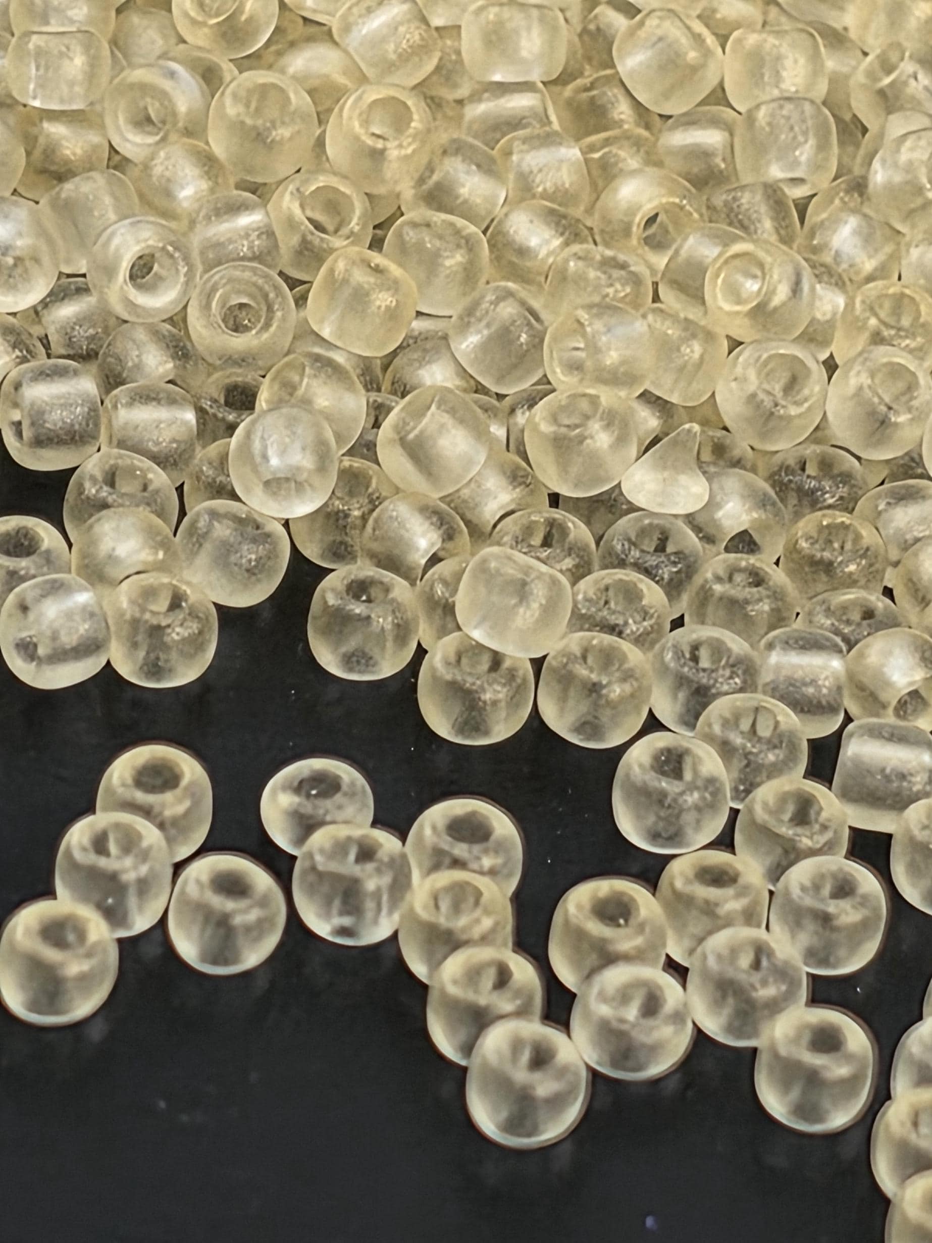 a close-up view of numerous transparent, clear beads scattered on a dark background.