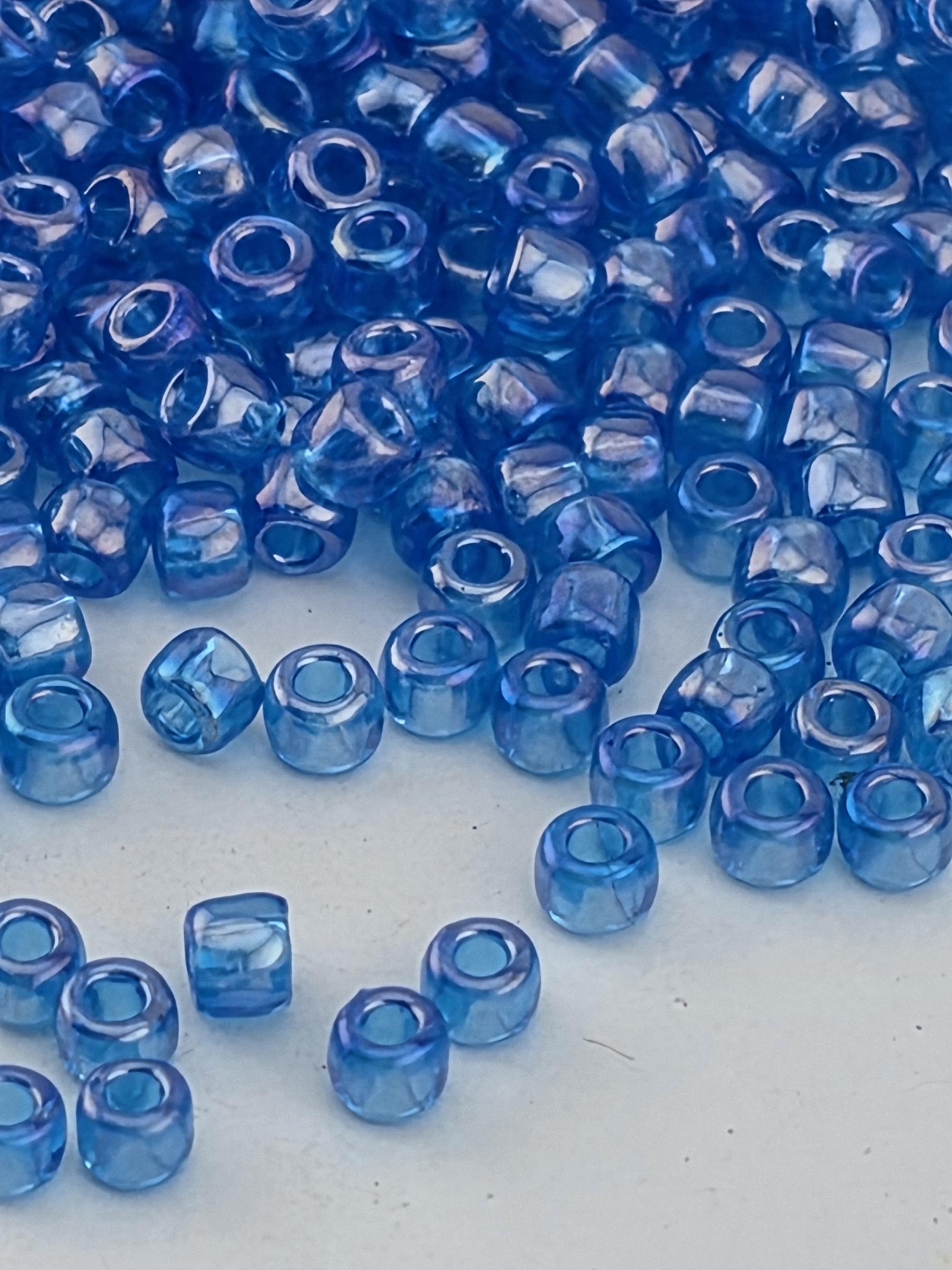 a collection of small, clear blue beads scattered on a white surface.
