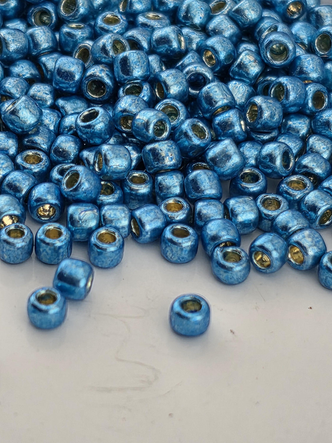 A close-up image of numerous blue beads scattered on a white surface.