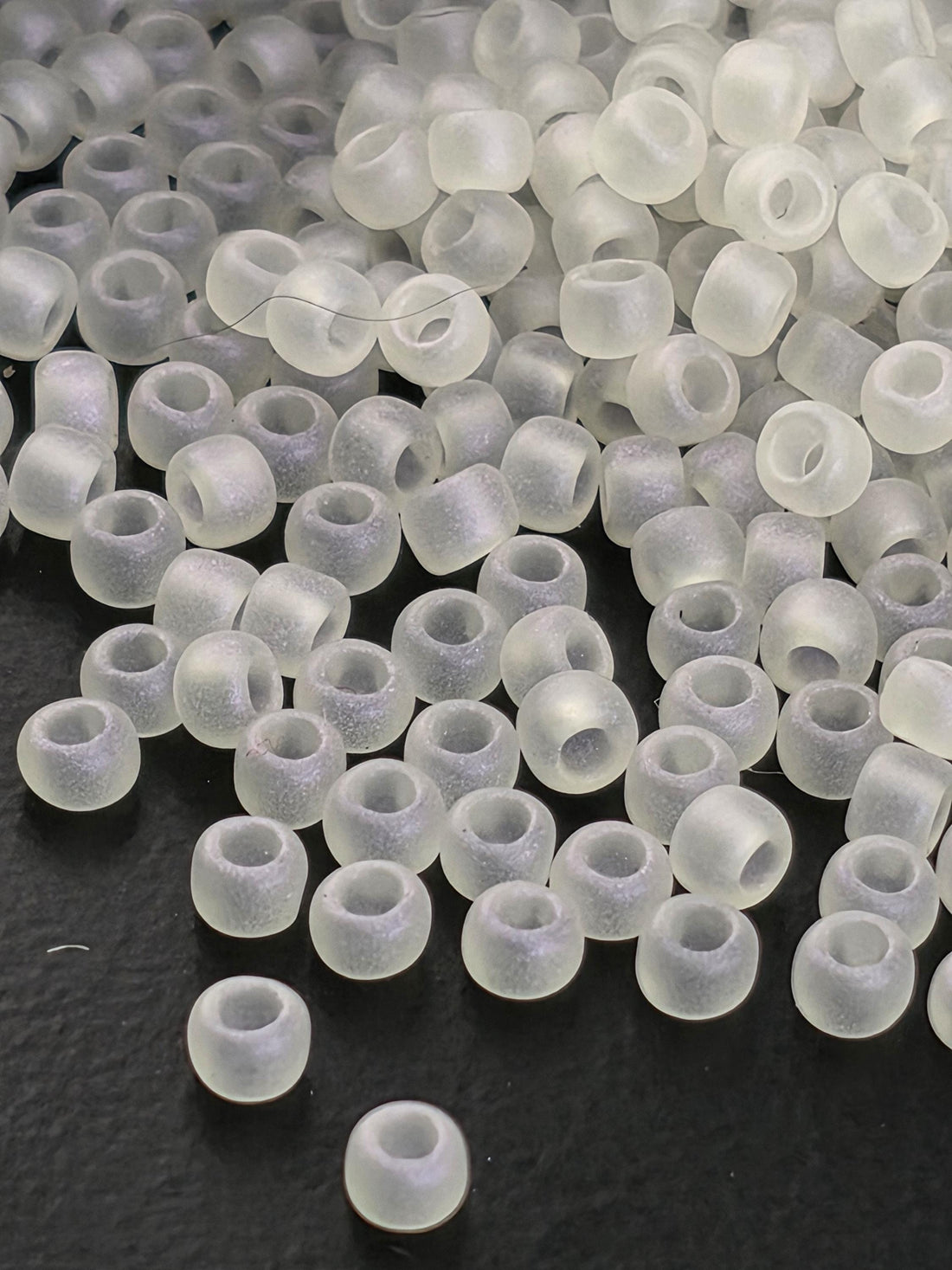 a collection of small, clear beads scattered on a dark surface.