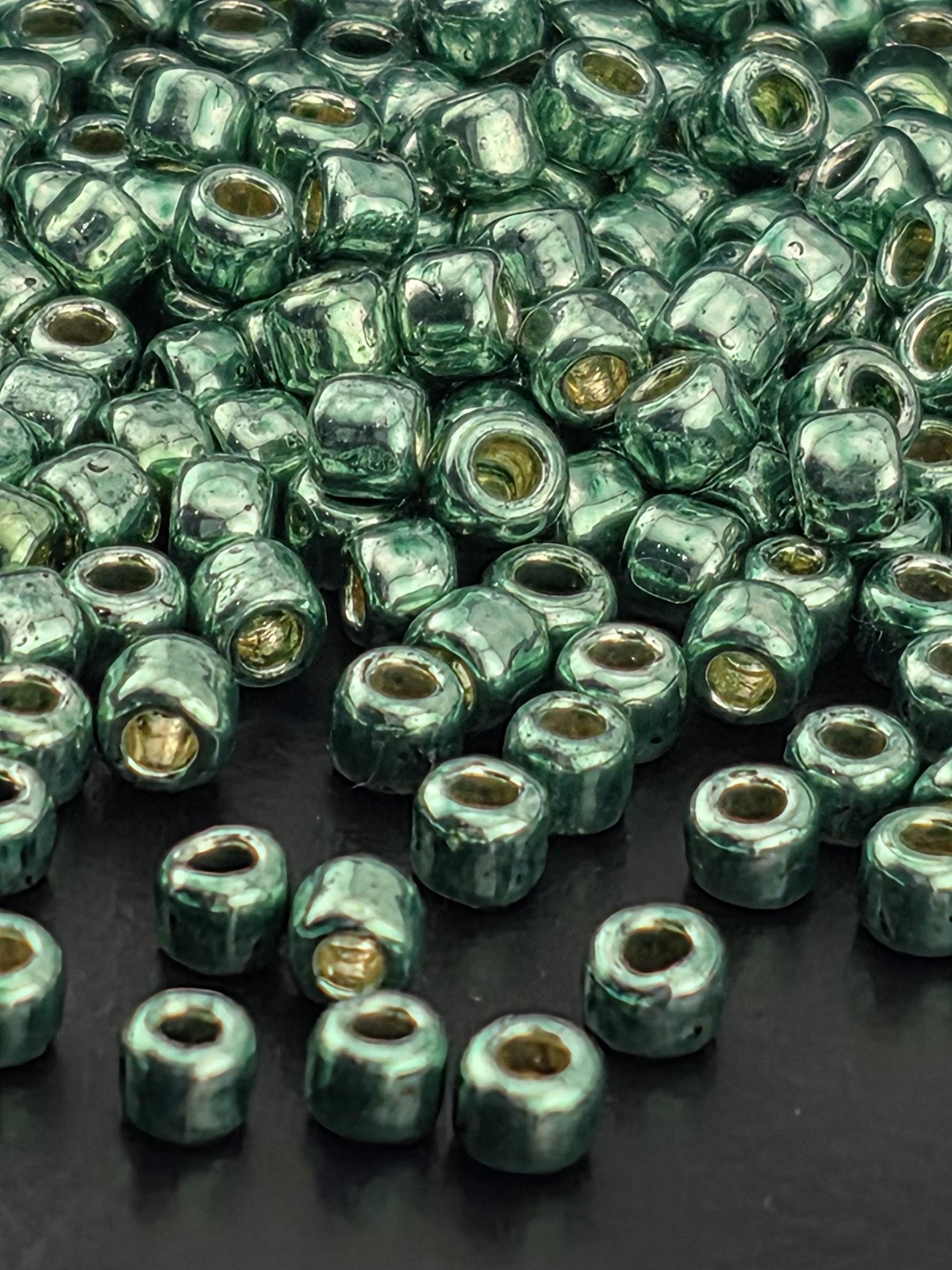 a close-up view of numerous green and gold beads scattered on a dark surface.