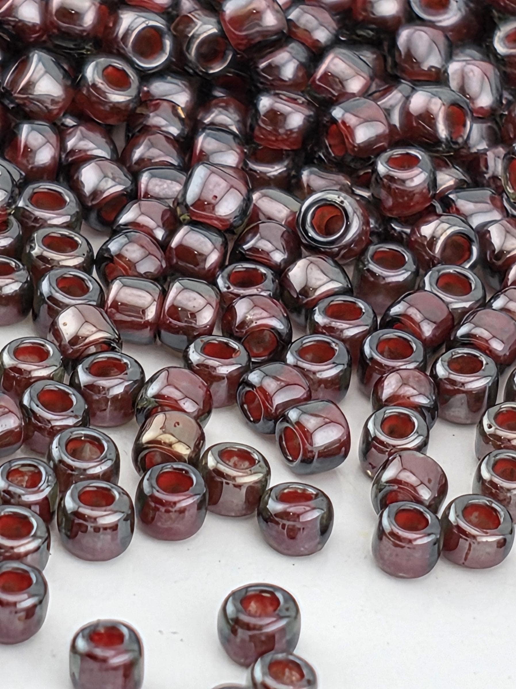 a large number of small, round beads in various shades of red, scattered across a surface.