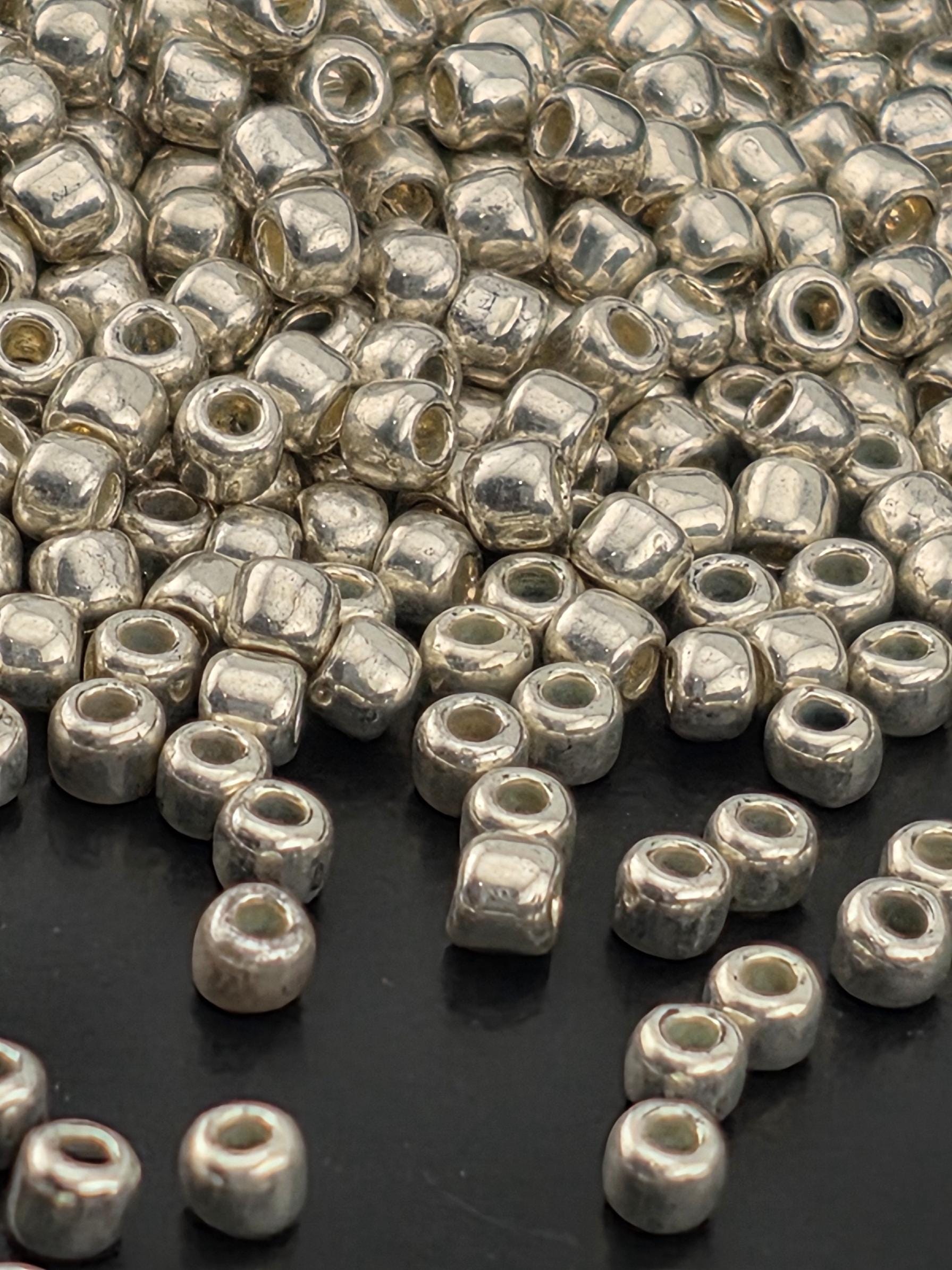 a close-up view of numerous silver-colored metal beads scattered on a dark surface.