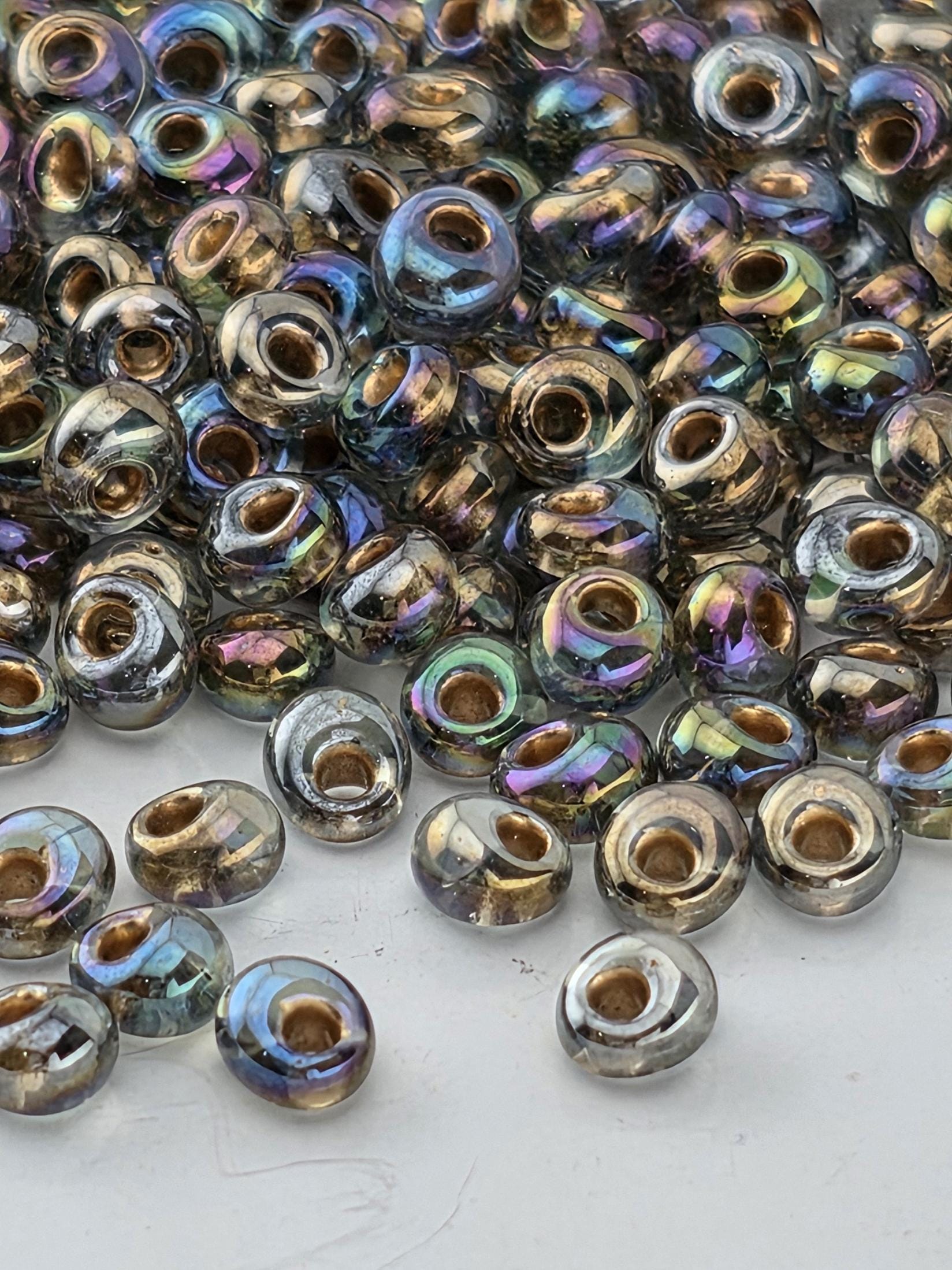 a close-up view of numerous glass beads scattered on a white surface. The beads have a variety of colors and sizes, creating a visually appealing and diverse collection.