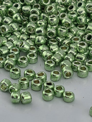 a close-up view of numerous small, shiny green beads or beads scattered on a surface.