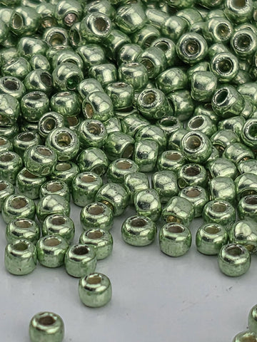 A close-up image of numerous small, shiny green beads or beads scattered on a surface.