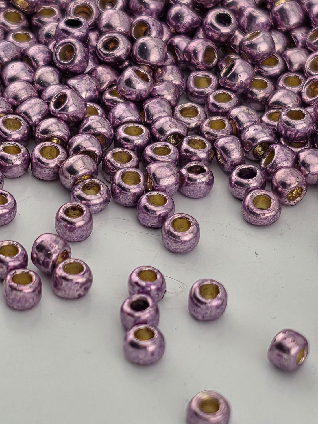 a close-up view of numerous small, shiny purple beads scattered across a white surface.