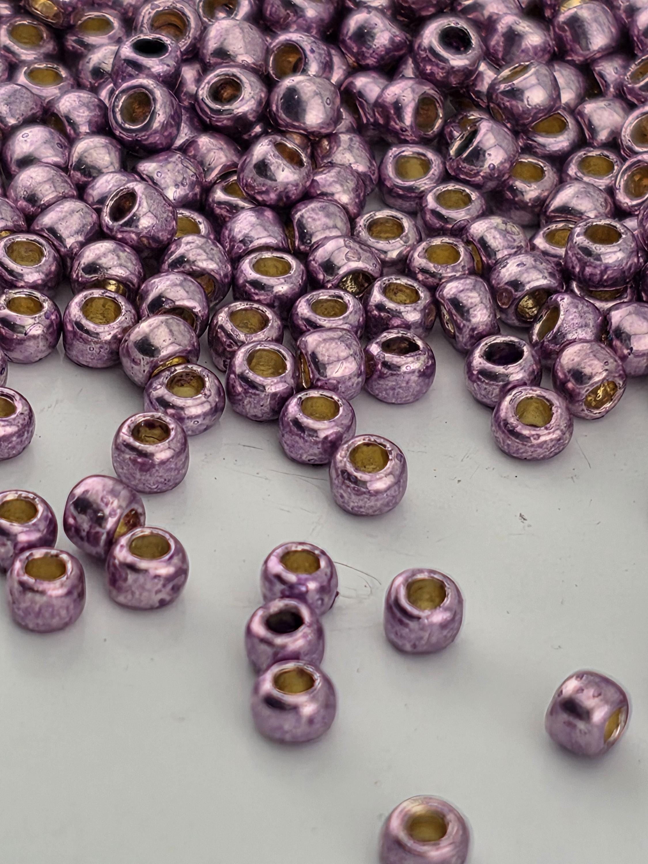 a close-up view of numerous small, shiny purple beads scattered across a white surface.