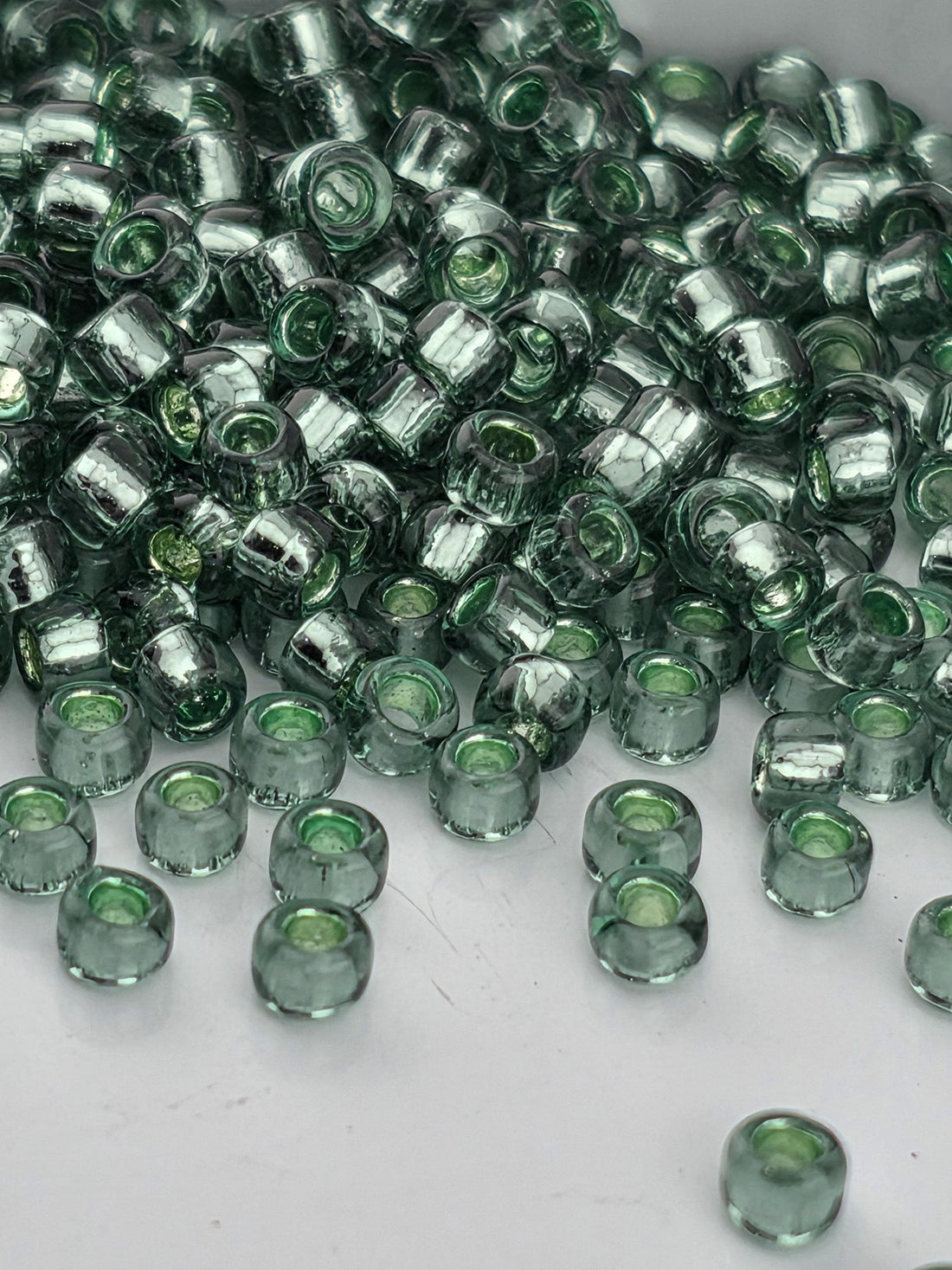 A pile of green glass beads on a white surface.