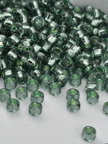 A pile of green glass beads on a white surface.