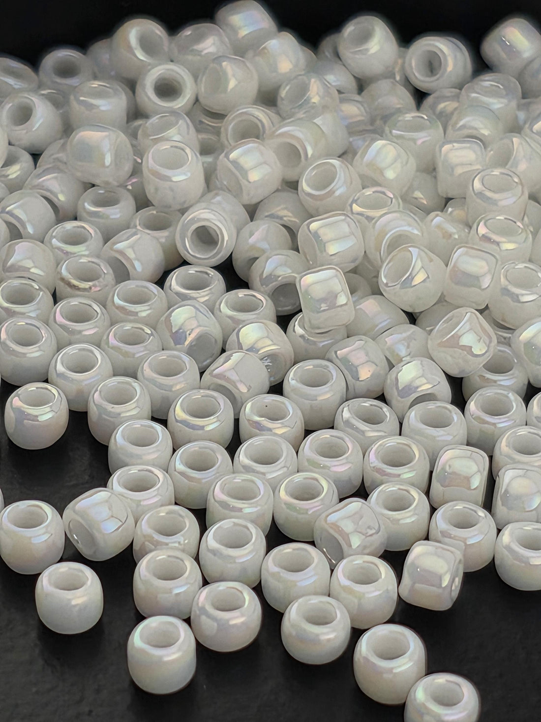 A close-up image of numerous small, white beads scattered on a dark surface.