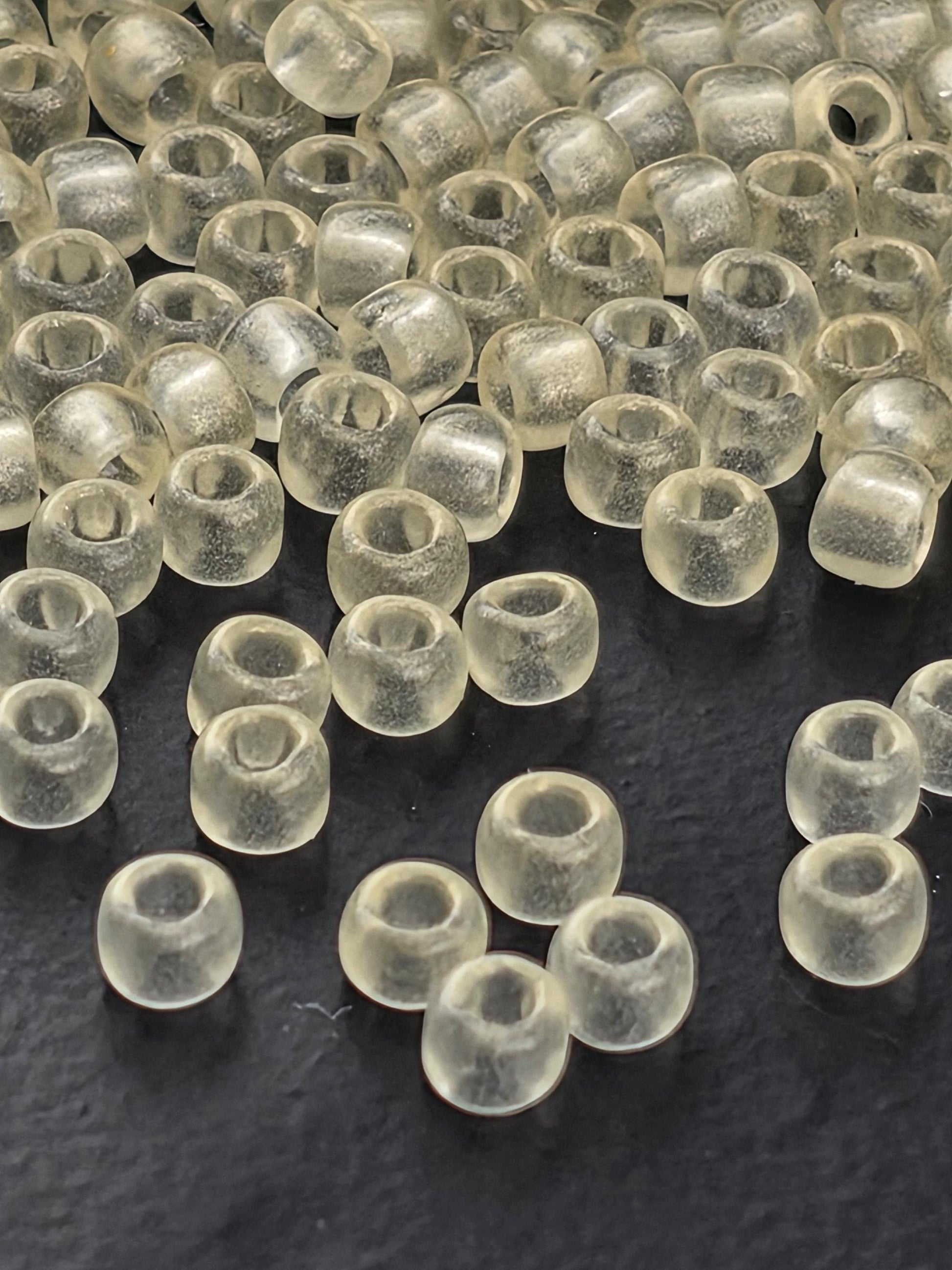 a collection of clear, transparent beads scattered on a dark surface.