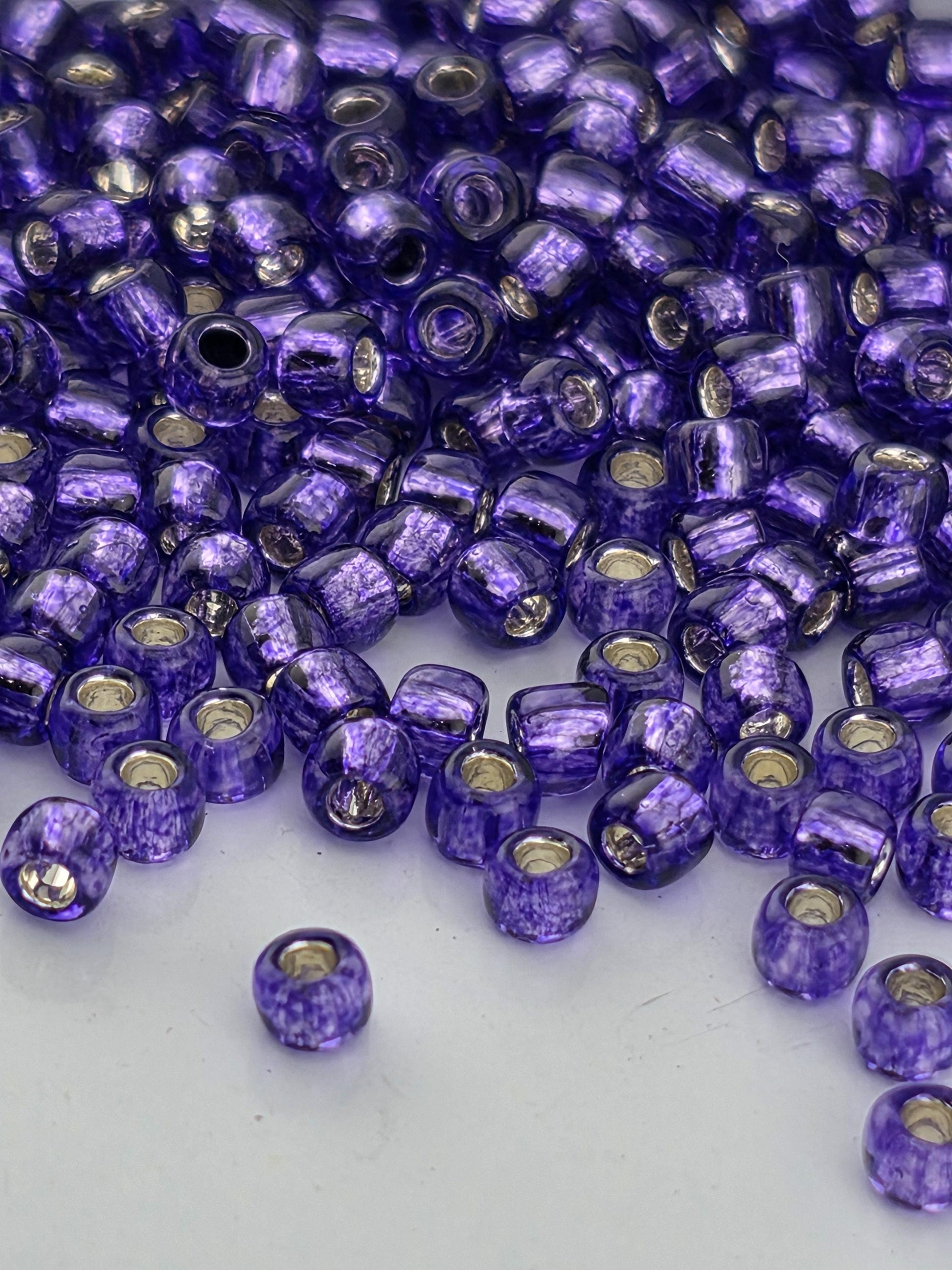 a close-up view of numerous purple glass beads scattered on a white surface.