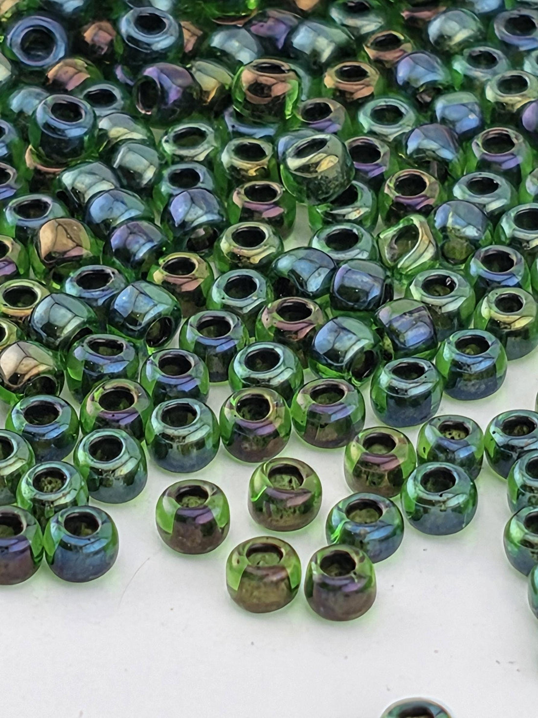 a close-up view of numerous green and purple glass beads scattered across a surface.