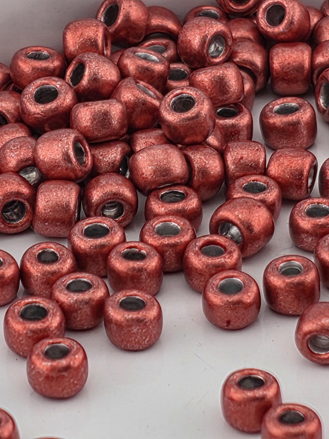 a close-up view of numerous red beads or beads with a metallic appearance, scattered across a surface.