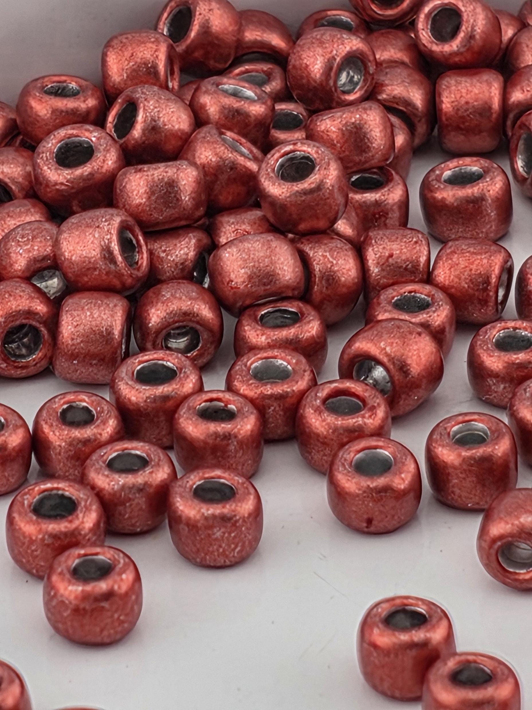 a close-up view of numerous red beads or beads with a metallic appearance, scattered across a surface.