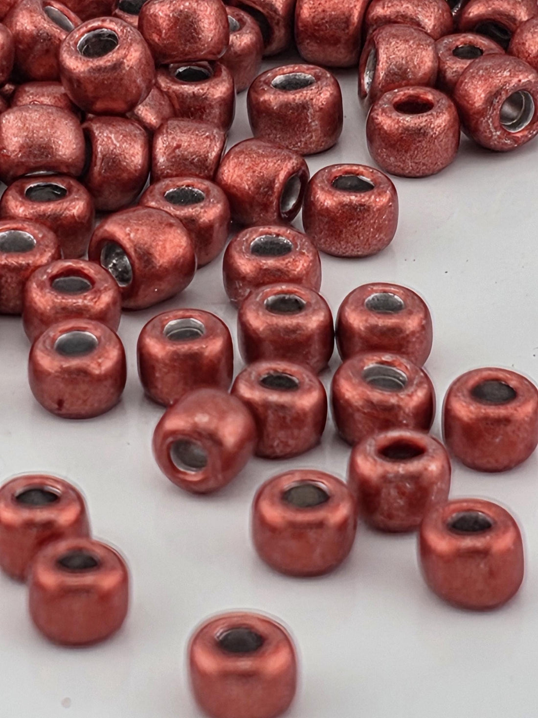 a close-up view of numerous red beads or beads with a metallic appearance, scattered across a surface.