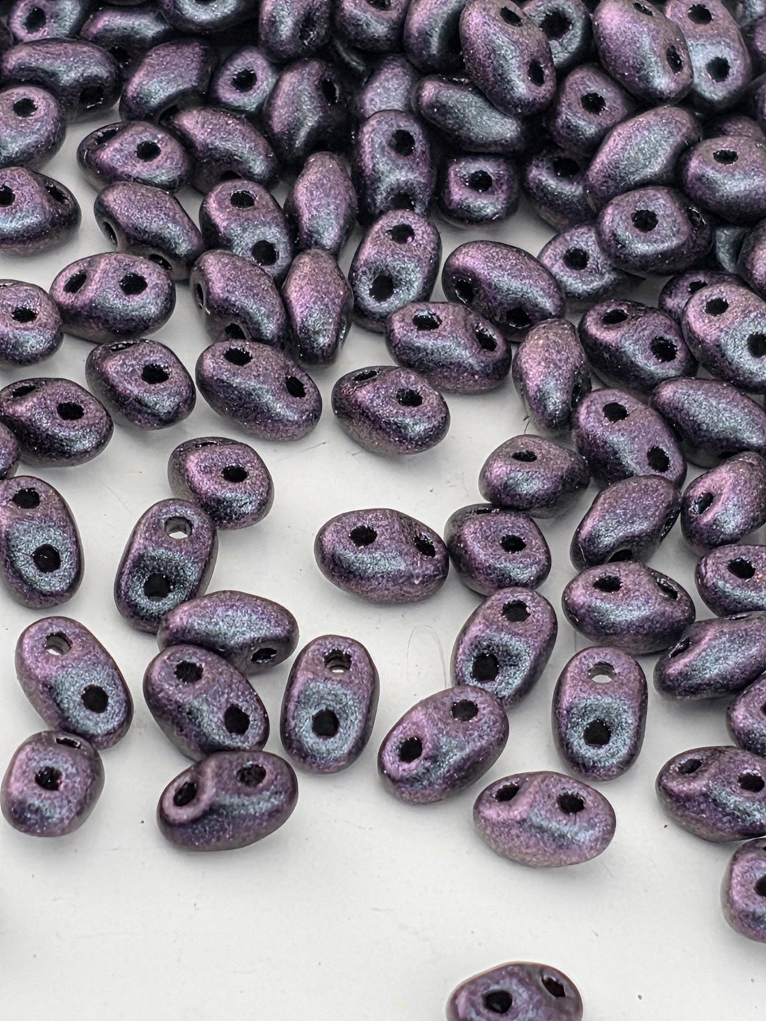 a collection of small, purple beads scattered across a white surface.