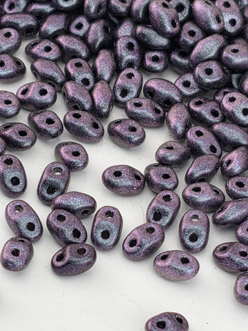 a collection of small, purple beads scattered across a white surface.