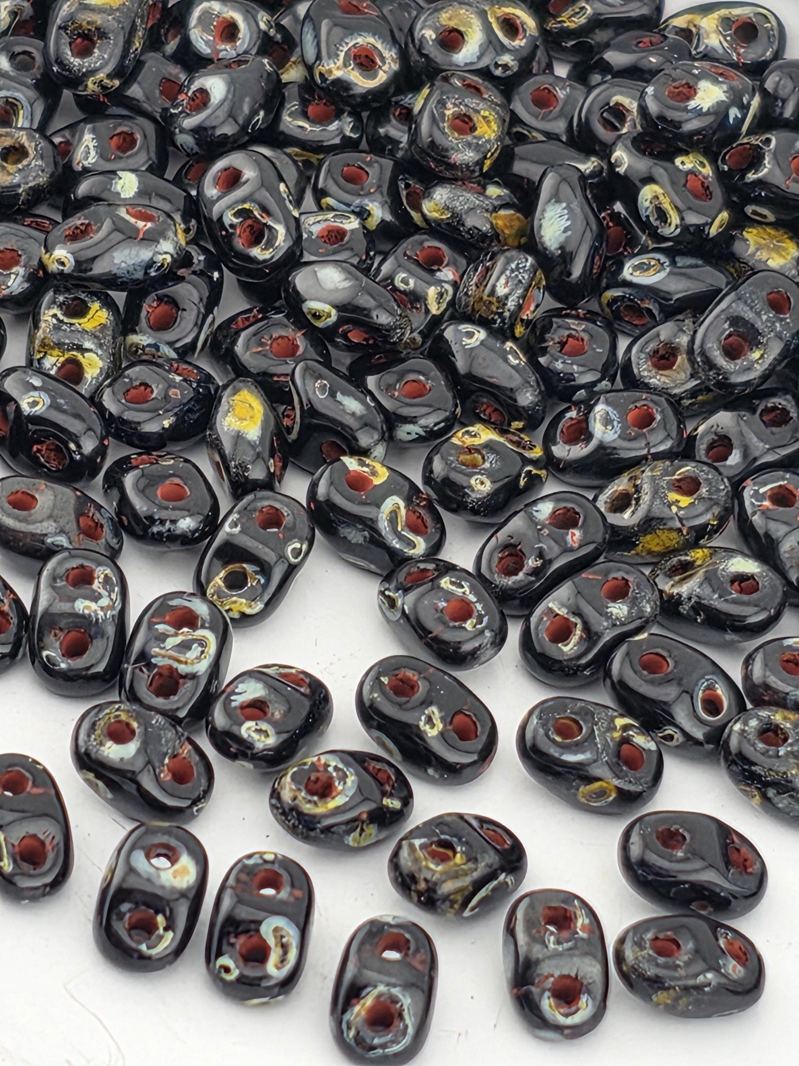 a collection of black beads with red and yellow accents, scattered across a white surface.