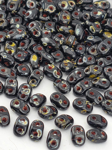 a collection of black beads with red and yellow accents, scattered across a white surface.