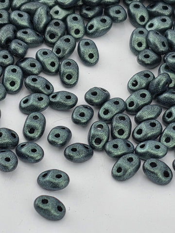 a collection of small, shiny, and metallic beads scattered on a white surface.