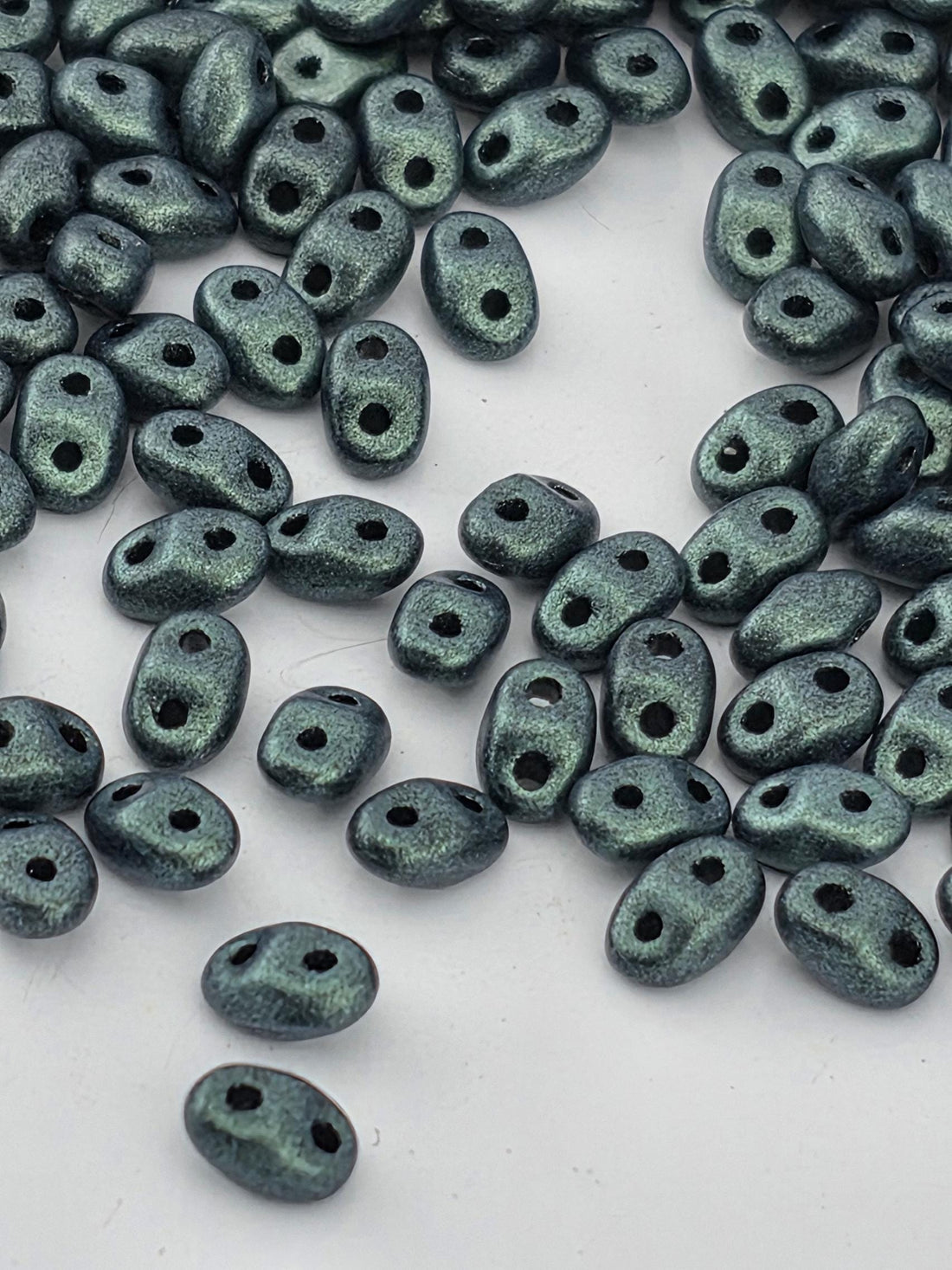 a collection of small, shiny, and metallic beads scattered on a white surface.