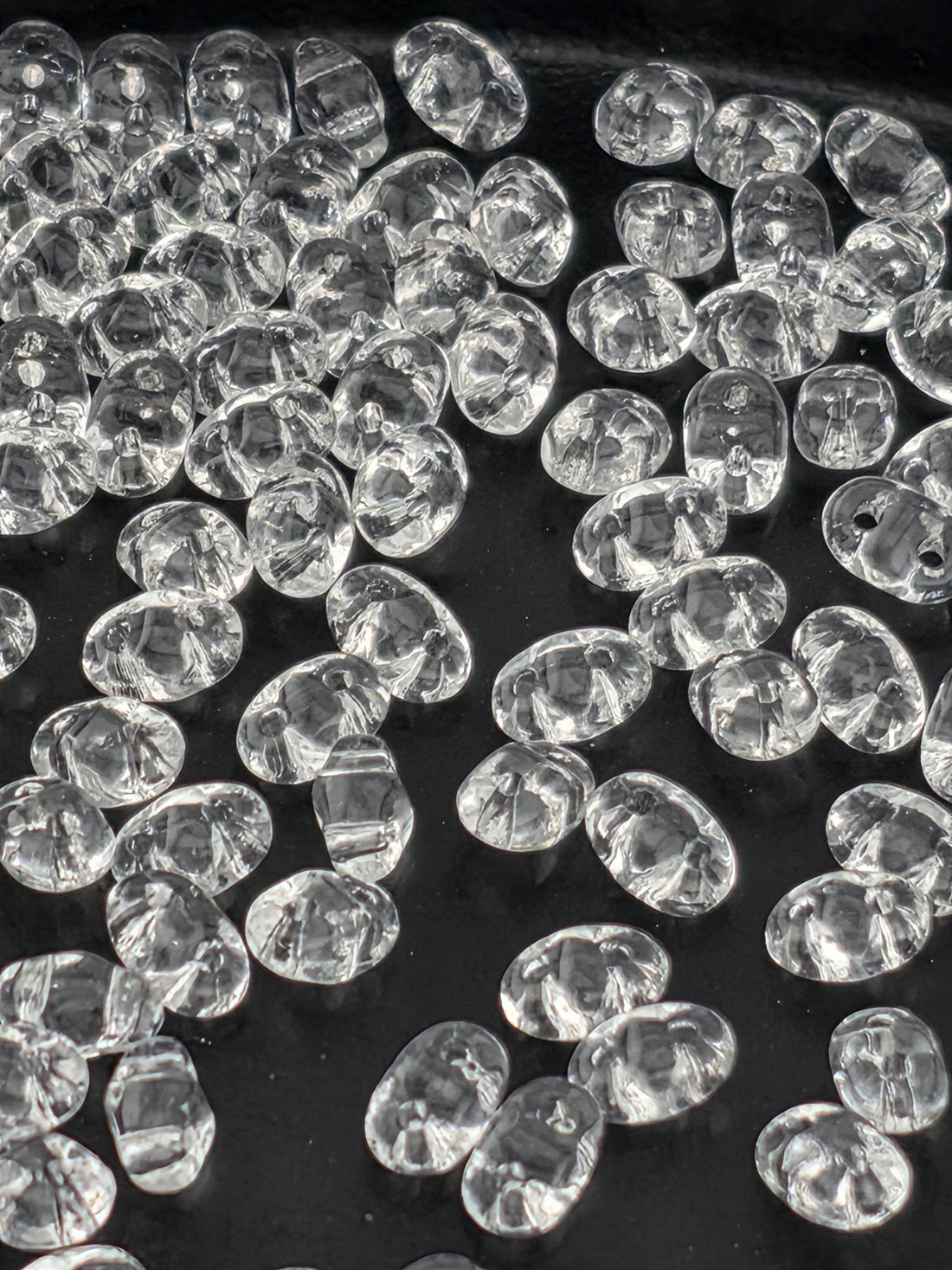 a close-up view of numerous clear, transparent beads scattered across a dark background.
