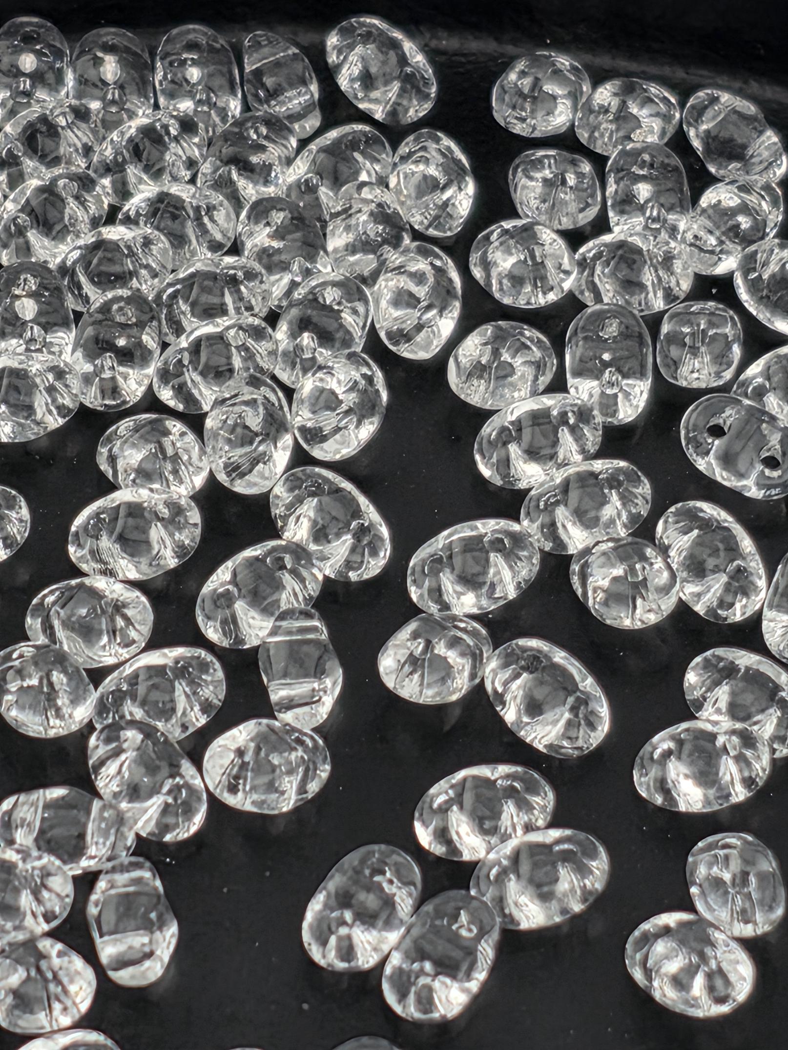 a close-up view of numerous clear, transparent beads scattered across a dark background.