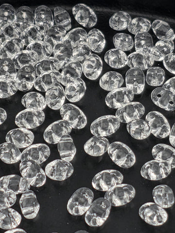 a close-up view of numerous clear, transparent beads scattered across a dark background.
