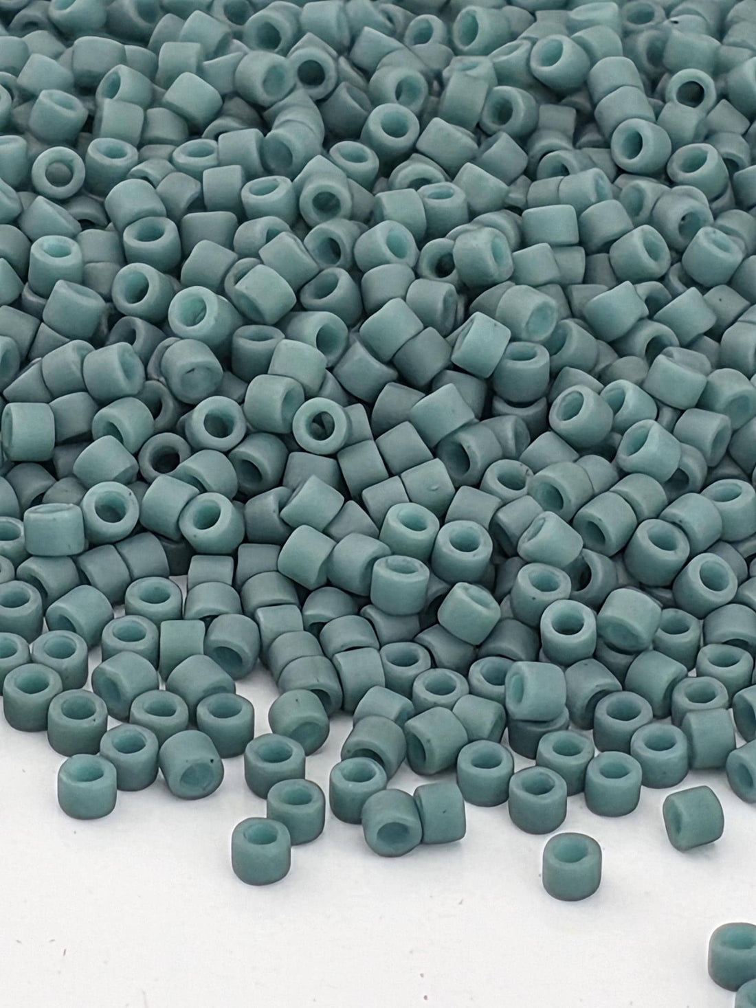 A close-up image of numerous small, light blue beads scattered across a surface.