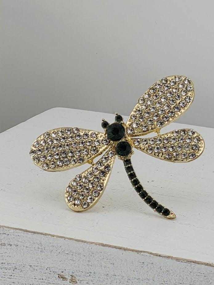 A decorative piece featuring a gold-colored dragonfly with black accents and sparkling crystal elements.