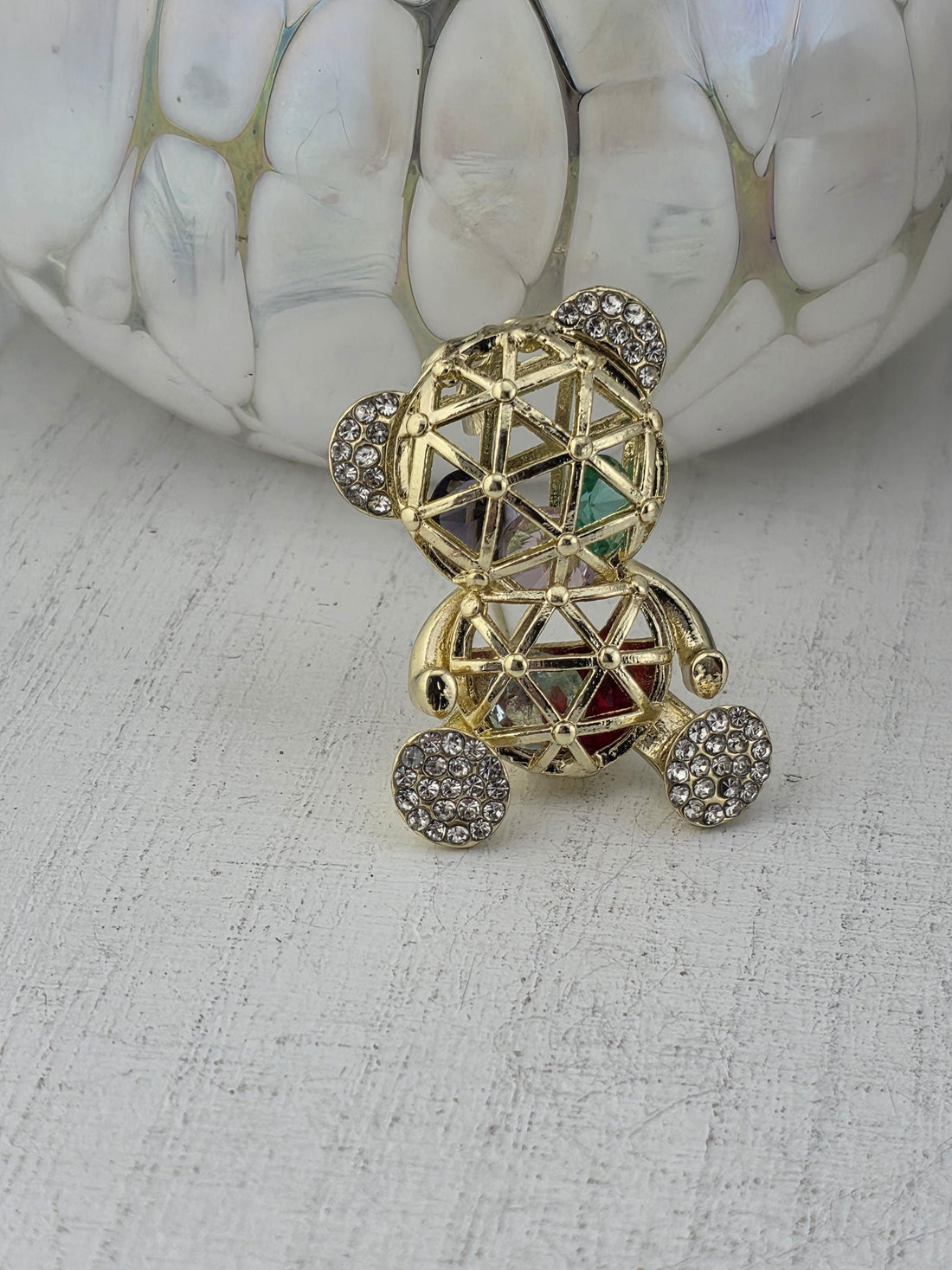 A decorative piece of jewelry with a metallic structure and gemstone elements, including a pendant and a ring.