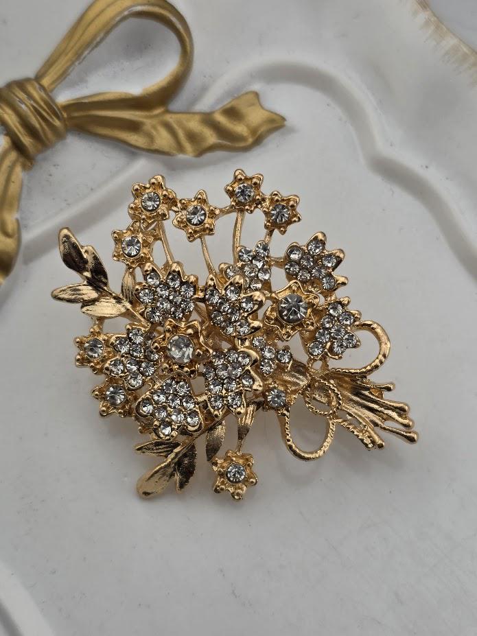 A decorative brooch with a floral design and sparkling crystal elements.