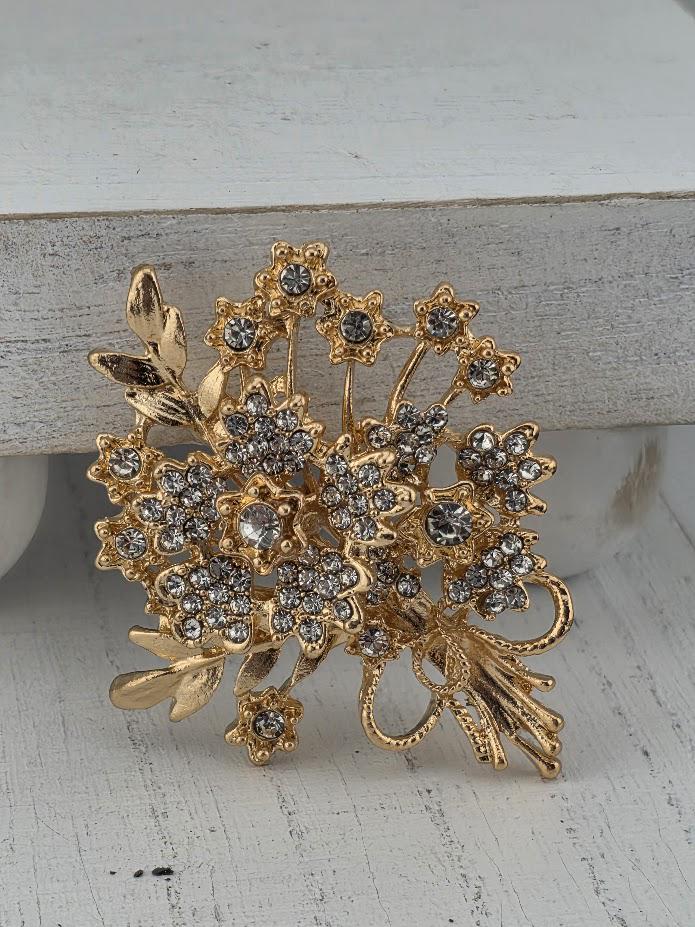 A decorative brooch with a floral design and sparkling crystal elements.