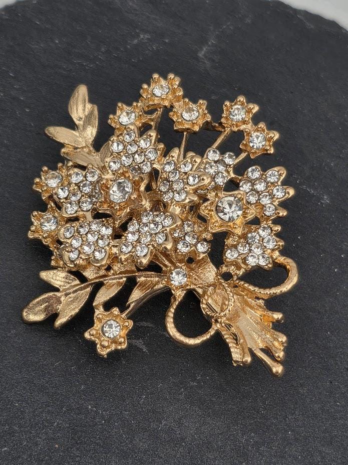 A decorative brooch with a floral design and sparkling crystal elements.