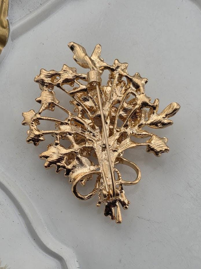A decorative gold brooch with an intricate floral design.