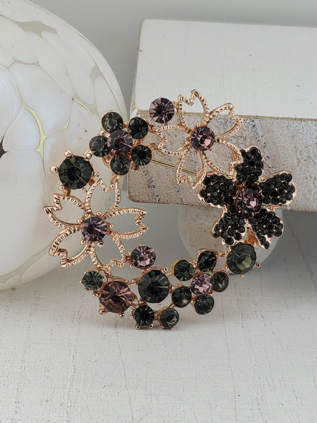 A decorative brooch with a floral design and black and purple gemstones.