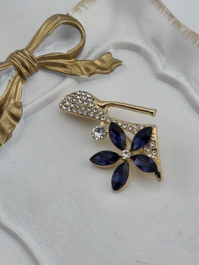 a gold-colored brooch with a flower-shaped design and a crystal flower on a white surface.