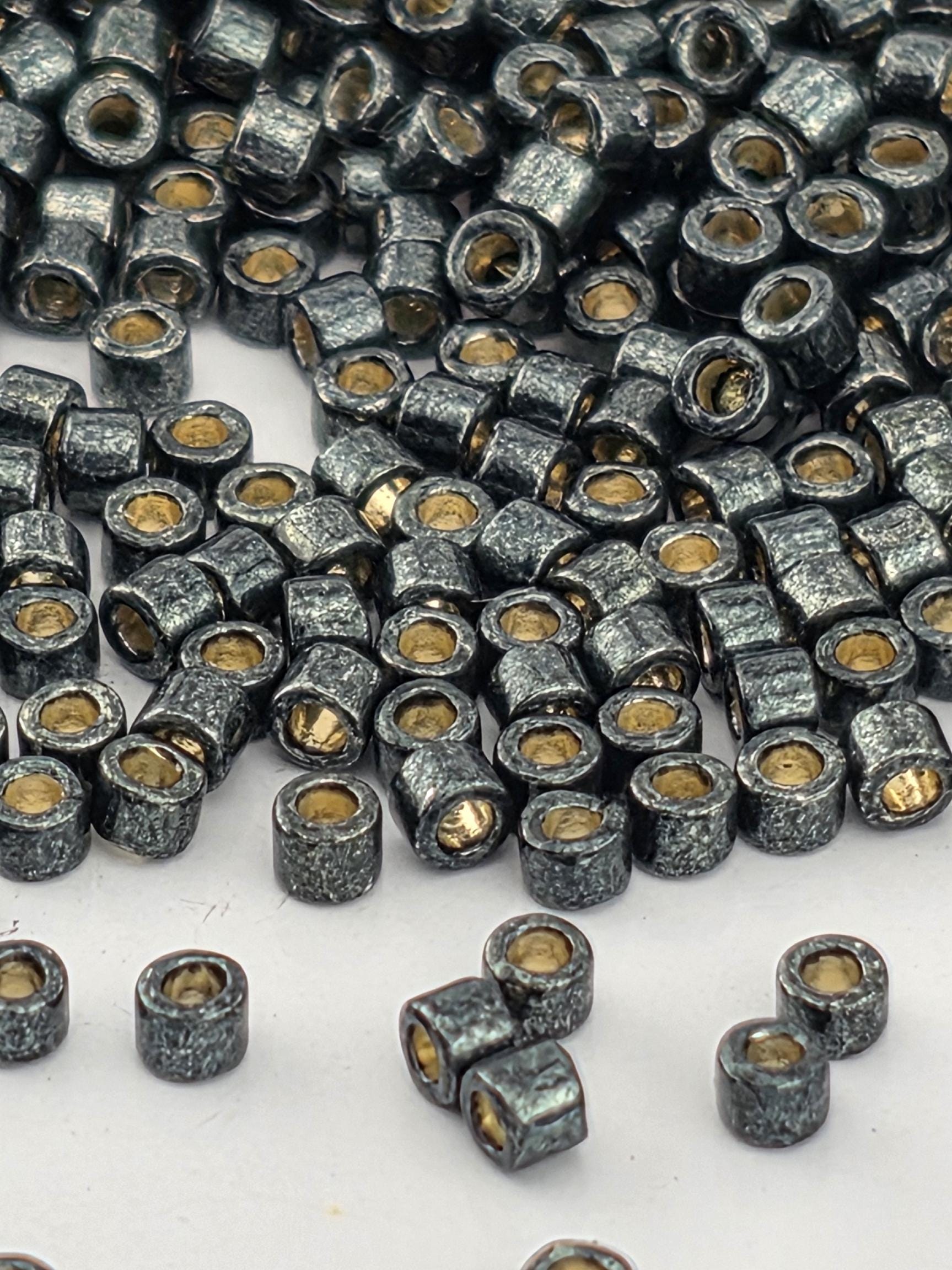 a close-up view of numerous small, round beads or metal objects with a metallic, textured appearance. The beads are scattered across a surface, with some overlapping each other.