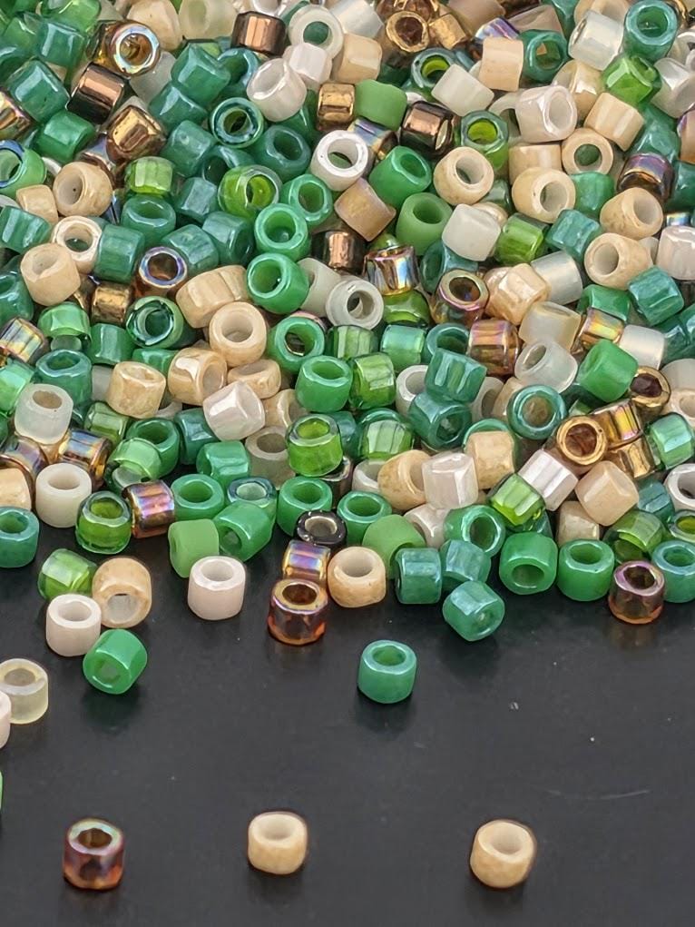 a large pile of multicolored beads, including green, white, and brown, scattered on a dark surface.