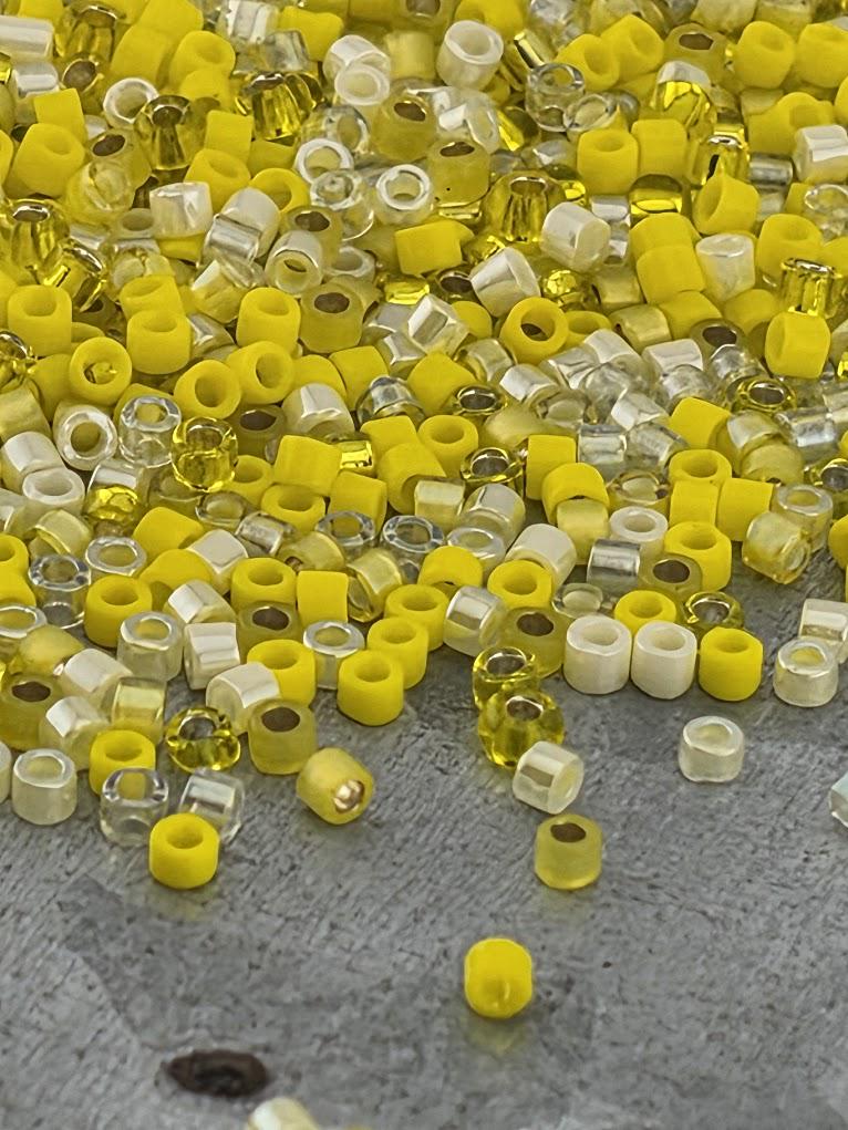 a large pile of yellow and white beads scattered on a gray surface.
