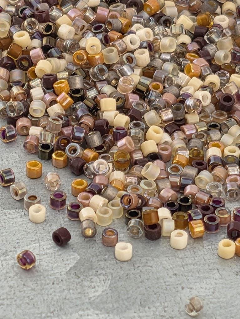 A large pile of multicolored beads, including various shades of brown, beige, and clear, scattered on a surface.
