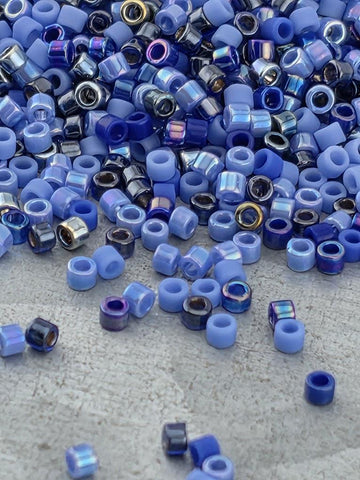 a large pile of blue and purple beads scattered on a surface, with some of the beads falling onto the ground.