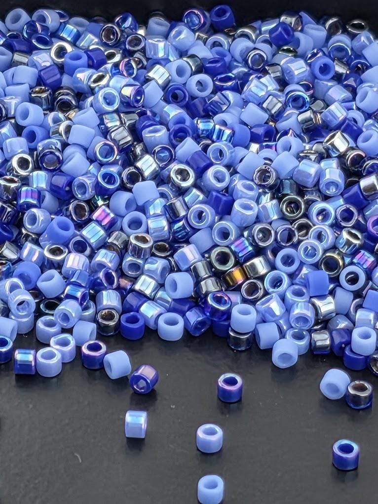 a large pile of blue and silver beads scattered on a dark surface.