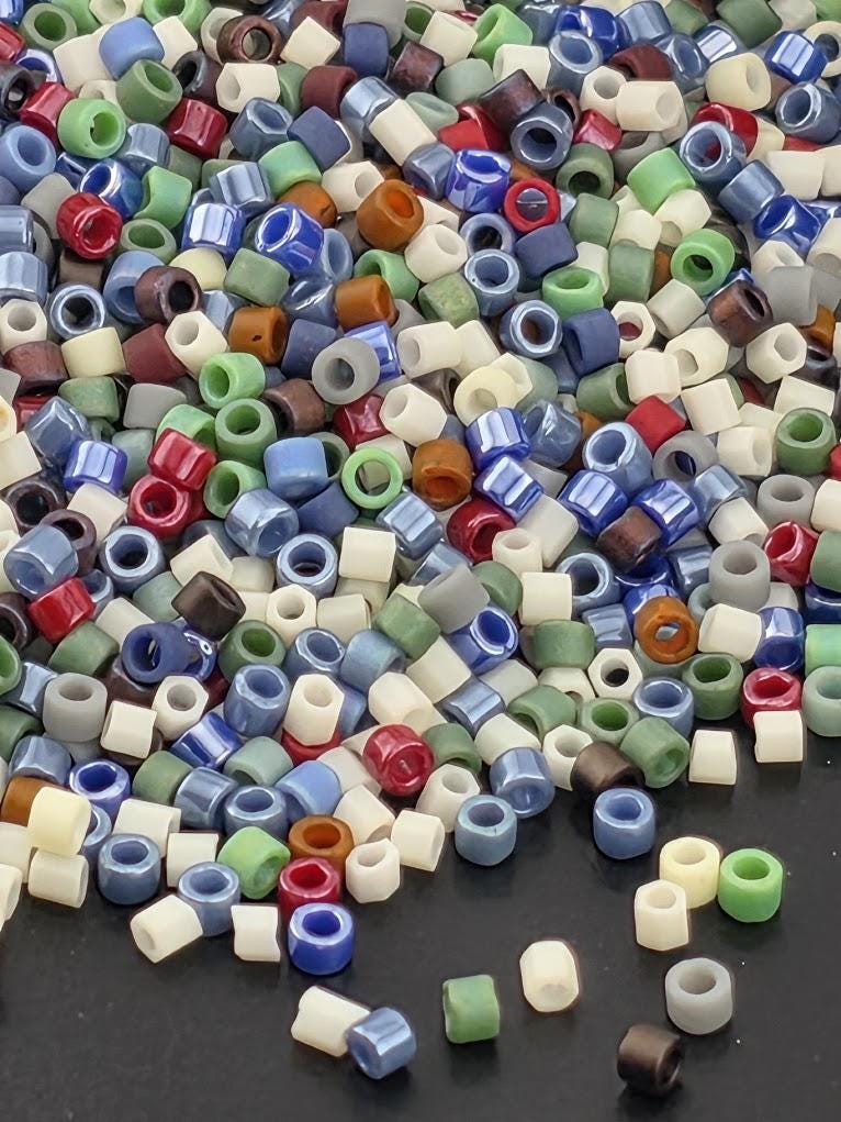 A colorful pile of multicolored beads, including various shades of blue, green, red, and white, scattered on a dark surface.
