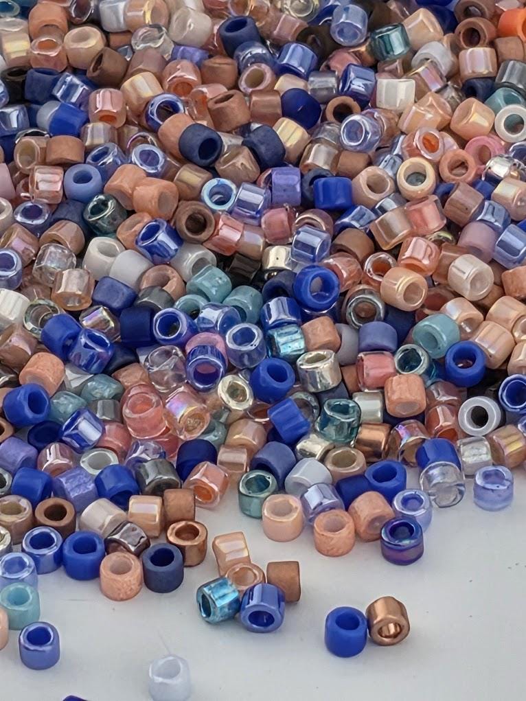 A large pile of multicolored beads, including various shades of blue, pink, orange, and purple, scattered across a surface.