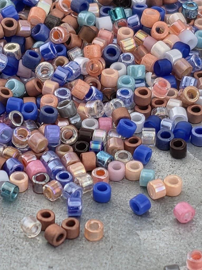 A colorful pile of various colored beads, including blue, pink, orange, and clear beads, scattered on a surface.